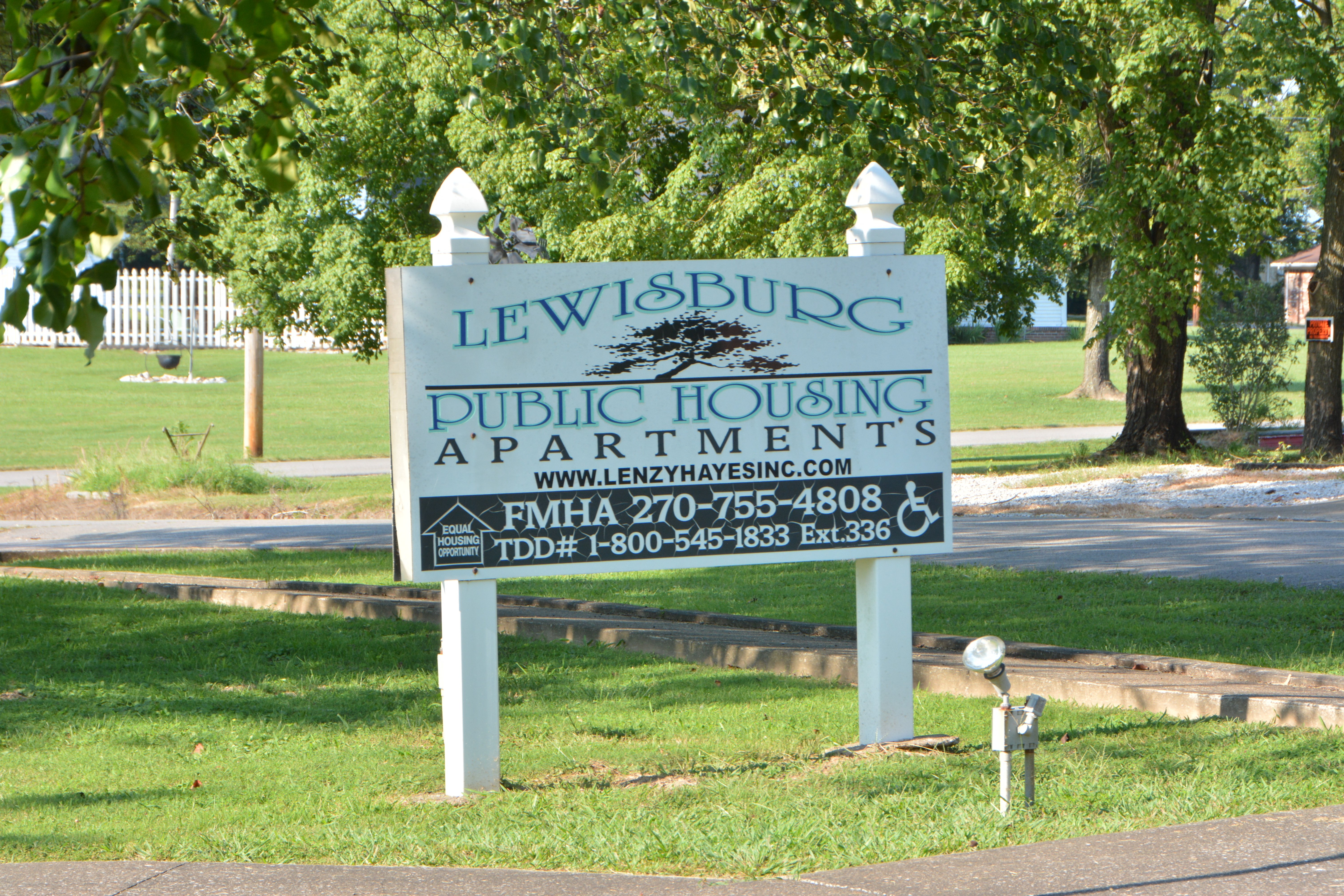 a sign for lewisburg public housing apartments in a park